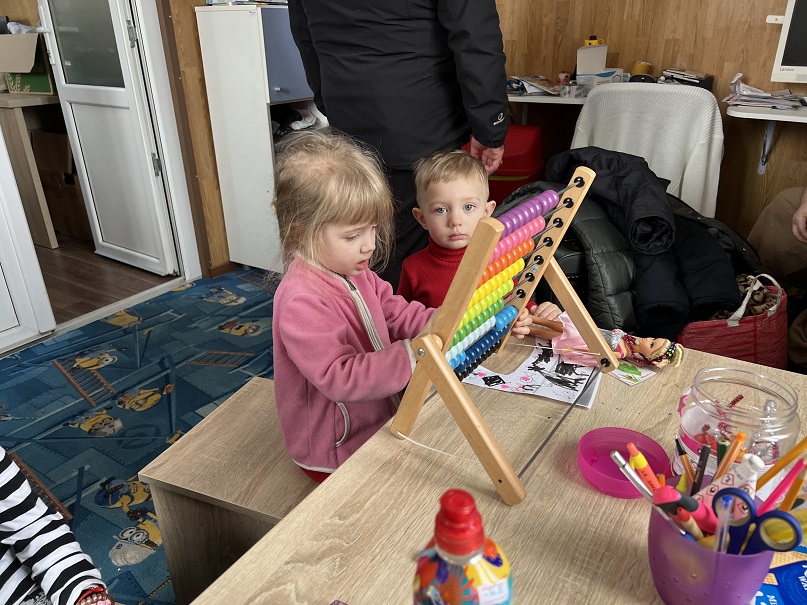 To ukrainske børn, leger med en kugleramme i et af Red Barnets børnevenlige område.