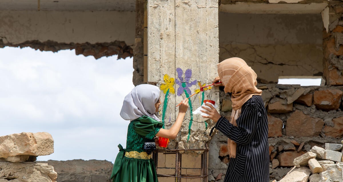 To piger fra Yemen maler farverige blomster på byens ruiner efter jordskælvet