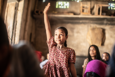 Pige rækker hånden i vejret i skole i Bangladesh
