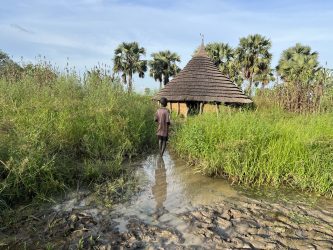 En dreng foran en oversvømmet hus i Sydsudan