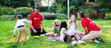 Fire børn og to voksne på græsplæne (modelbillede)