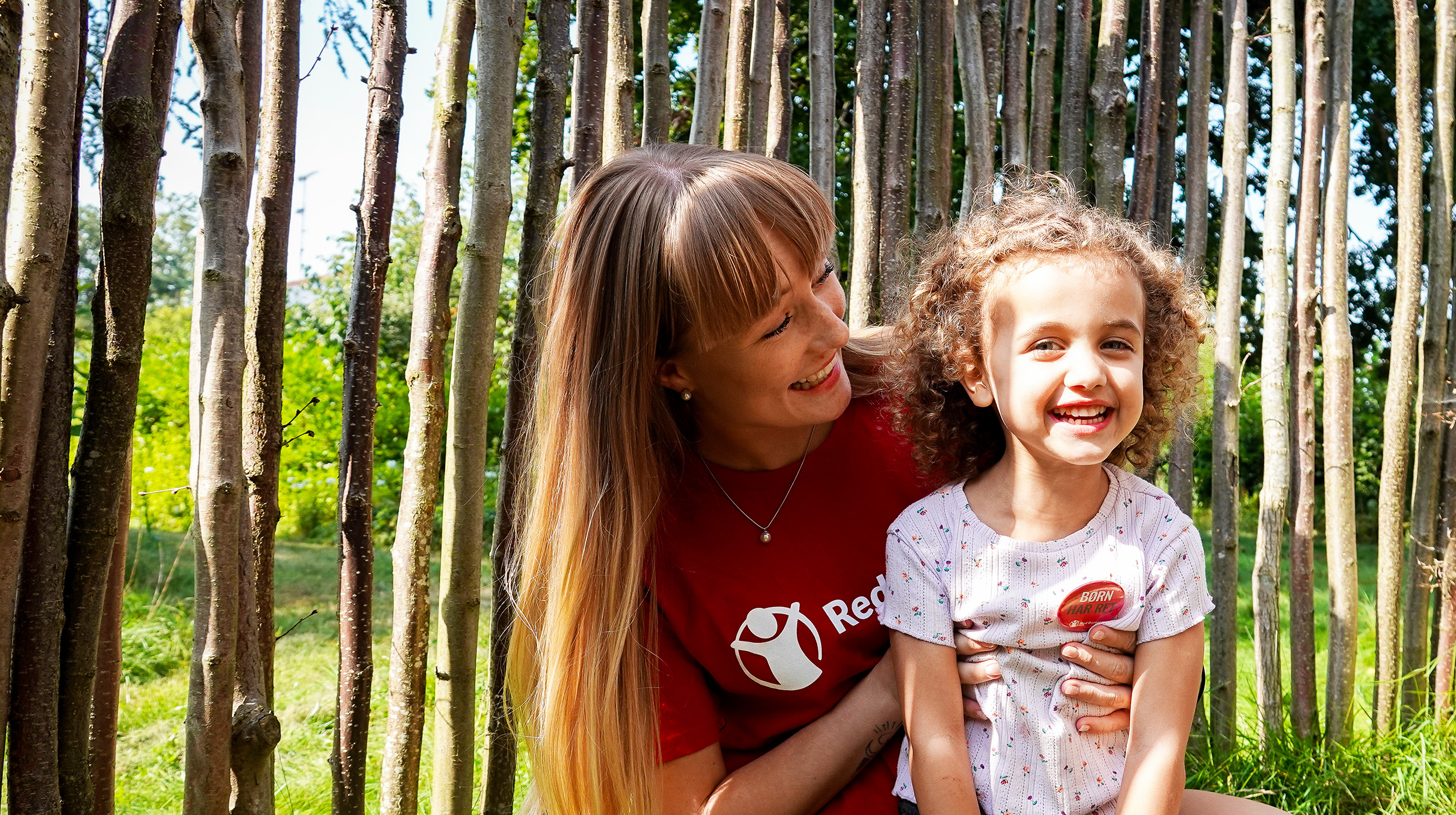 Barn og frivillig sidder udenfor - smiler (modelfoto)