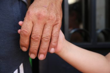 Voksen og barn holder i hånd